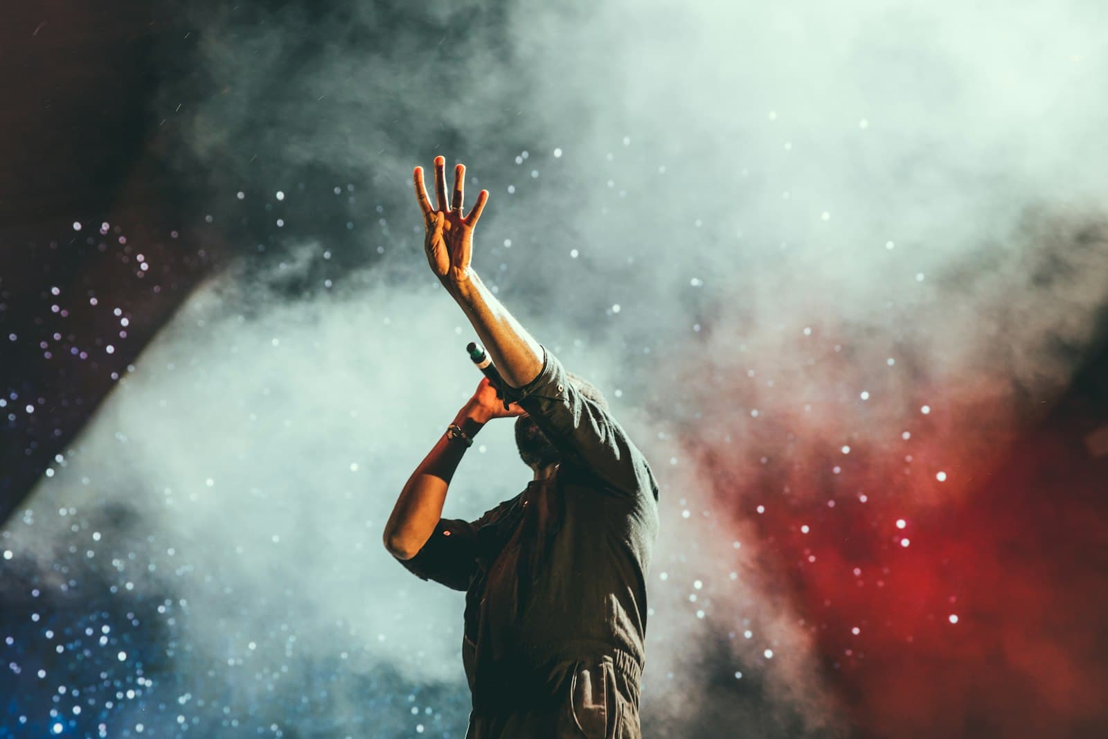 A performer on stage under smoke and lights at a concert